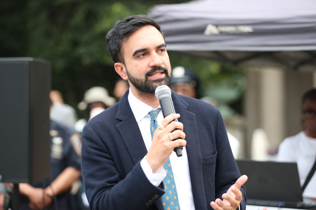 Zohran Mamdani speaking at a microphone.