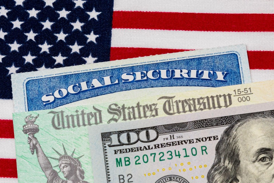 Social Security card, treasury check, and $100 bill on an American flag.