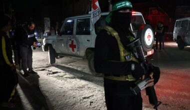 A Hamas fighter stands guard as a Red Cross vehicle transports newly released hostages in Rafah, in the southern Gaza Strip on November 28, 2023