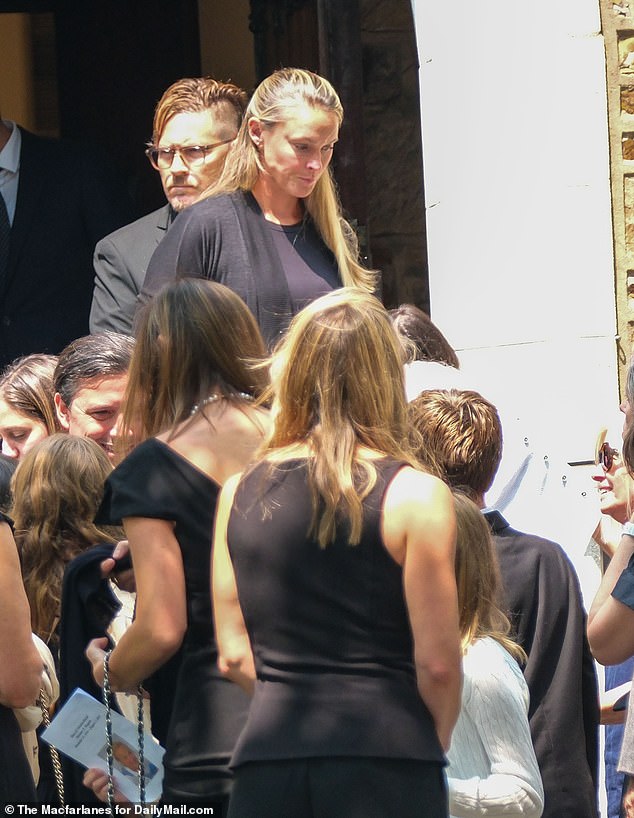 The mother-of-four is pictured exiting the church alongside fellow downcast mourners