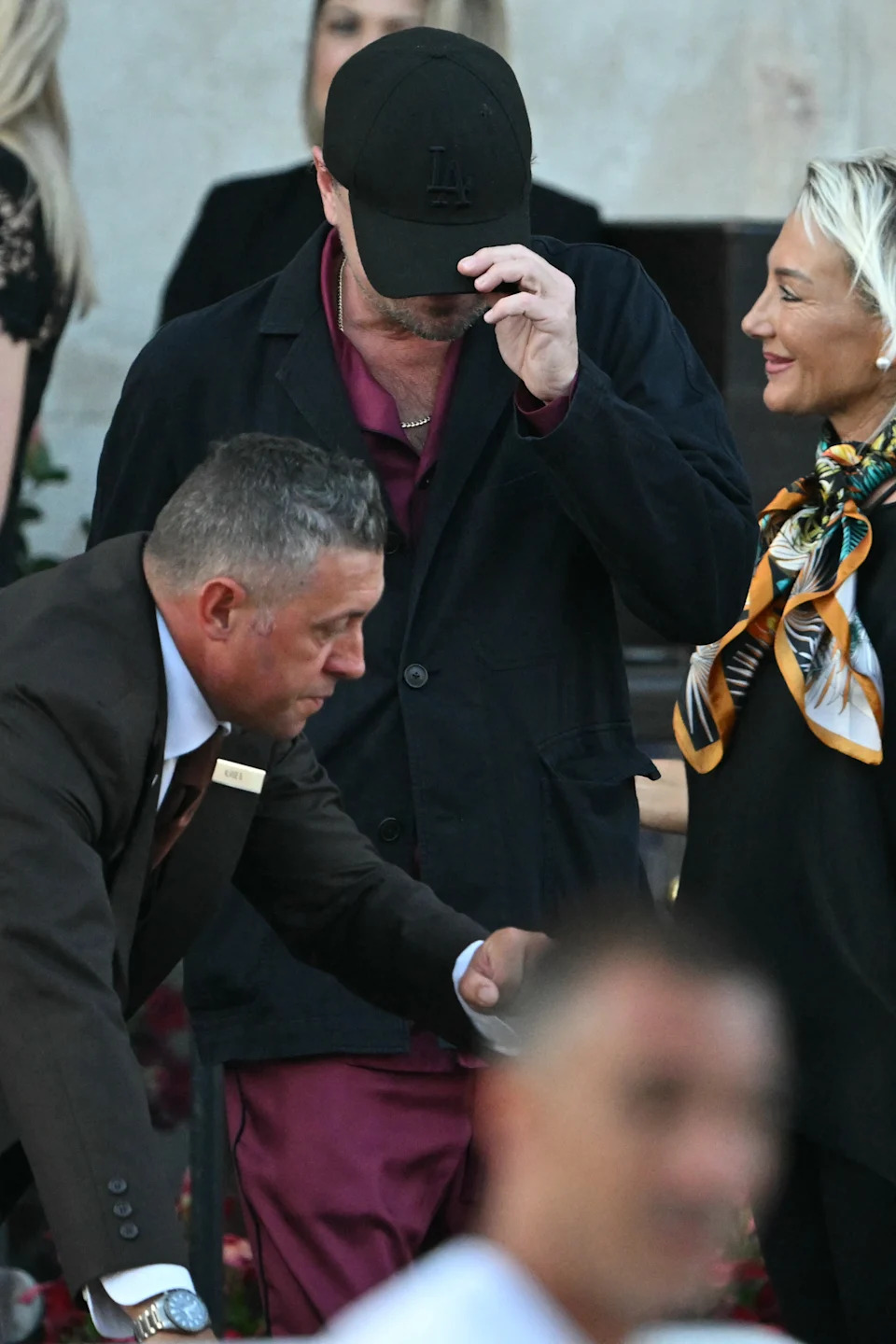 Leo in a casual dark coat and cap, obscuring his face, at an event