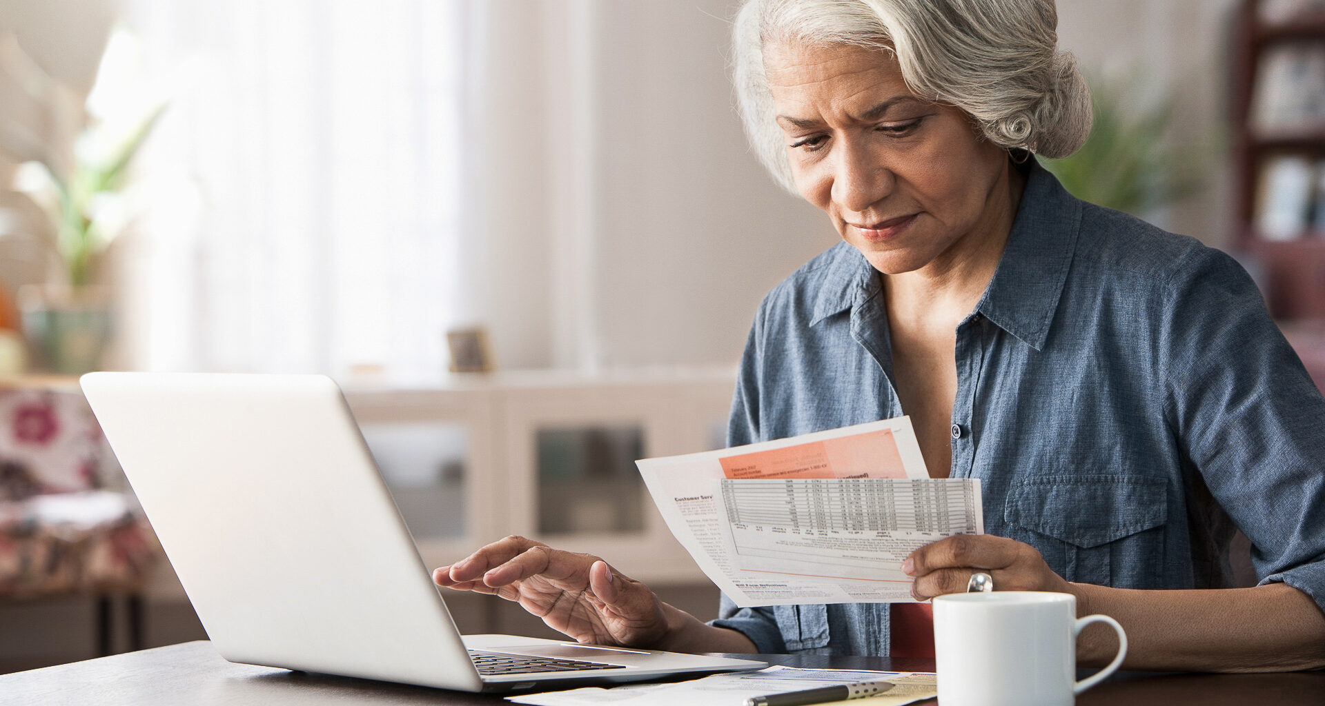 Older woman paying bills on laptop.