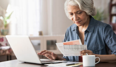 Older woman paying bills on laptop.