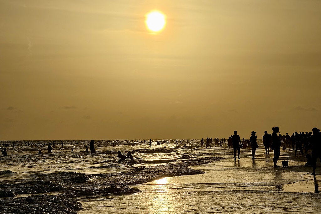 People walk on the beach at sunset at Siesta Beach in Sarasota, Florida, on June 6, 2025. At least 13 cases of Vibrio vulnificus infections have been reported in the state this summer, with four resulting in death.