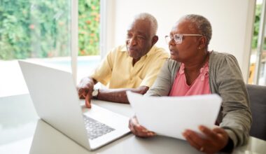 Shot of a senior african couple with a paper looking at a laptop at home.