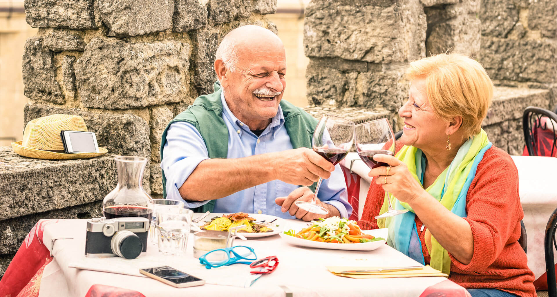 Senior couple having fun and eating at restaurant during travel - Mature man and woman wife in old city town bar during active elderly vacation - Happy retirement concept with retired people together.