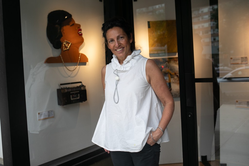 Art on the Ave founder Barbara Anderson poses for a portrait in front of an exhibit of local Lower East Side artists she helped curate.