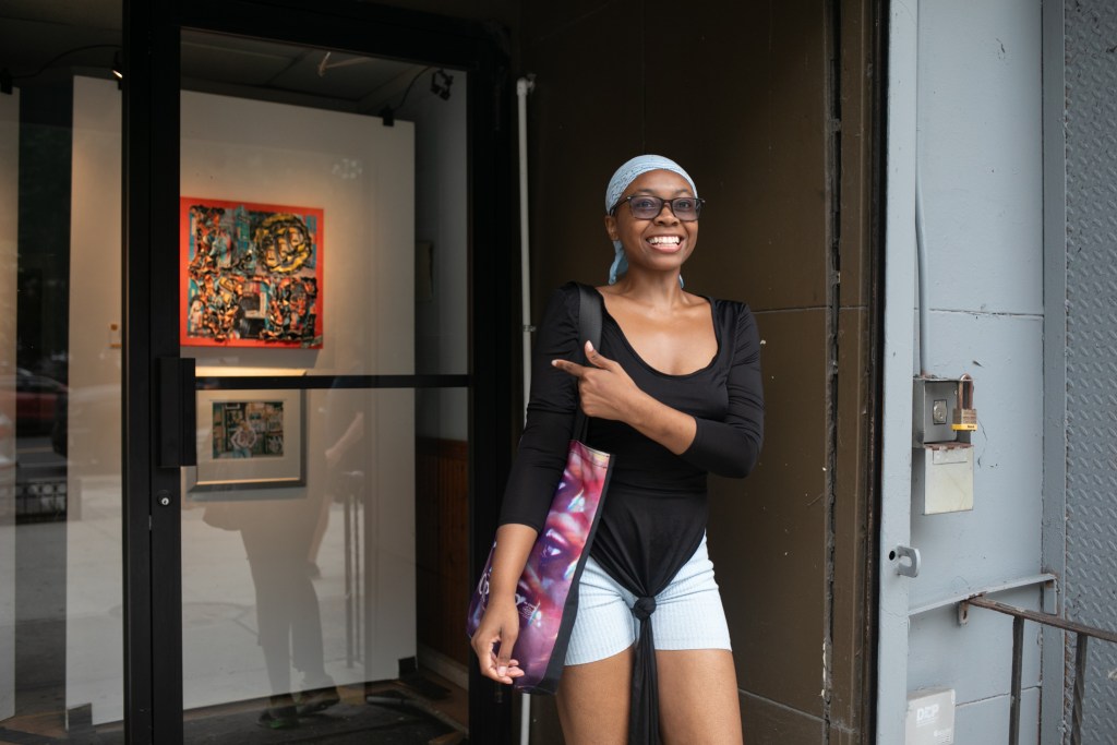 Photographer Ivy Shields smiles while standing near a portrait she had displayed in a gallery show next to the Alfred E. Smith Houses.