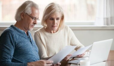A senior couple looks worried as they read financial statements.