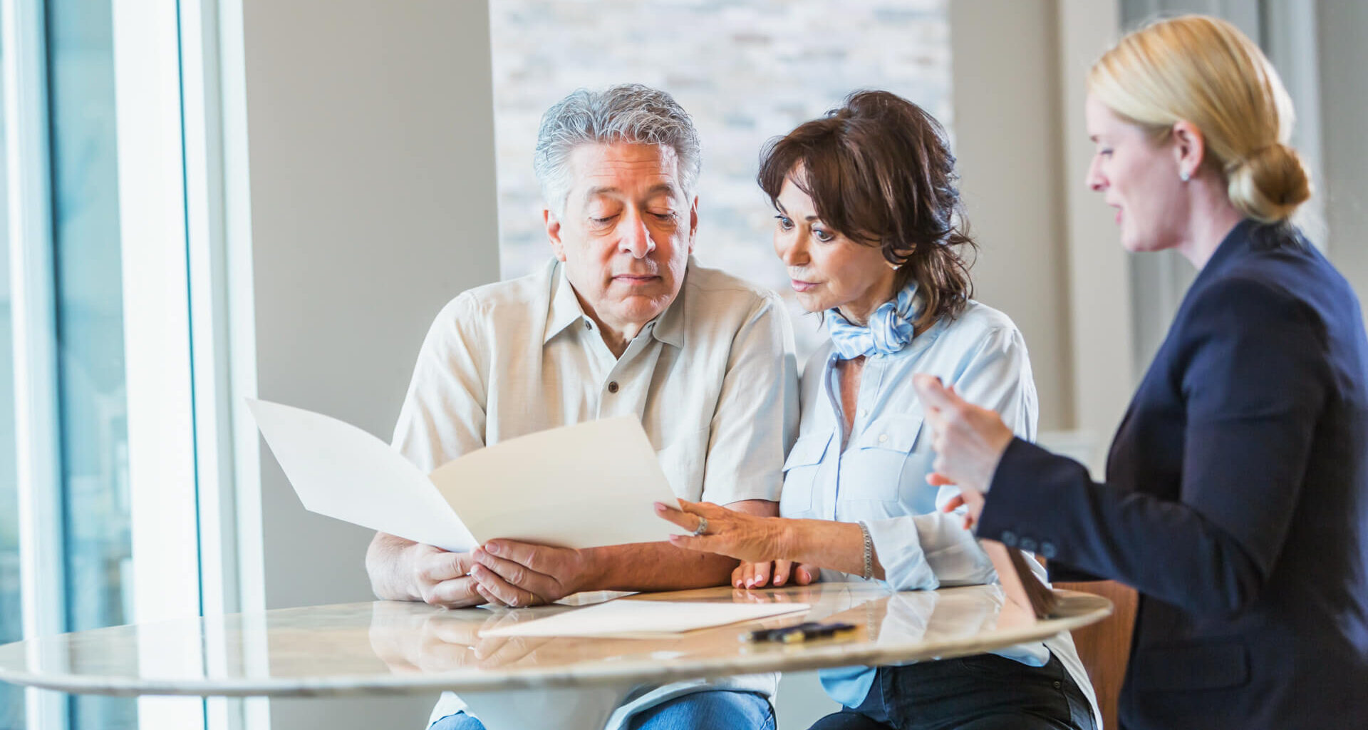 A senior couple sitting down with a personal consultant, perhaps a financial advisor to discuss their retirement plans, or maybe a realtor or insurance agent.