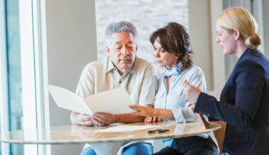 A senior couple sitting down with a personal consultant, perhaps a financial advisor to discuss their retirement plans, or maybe a realtor or insurance agent.