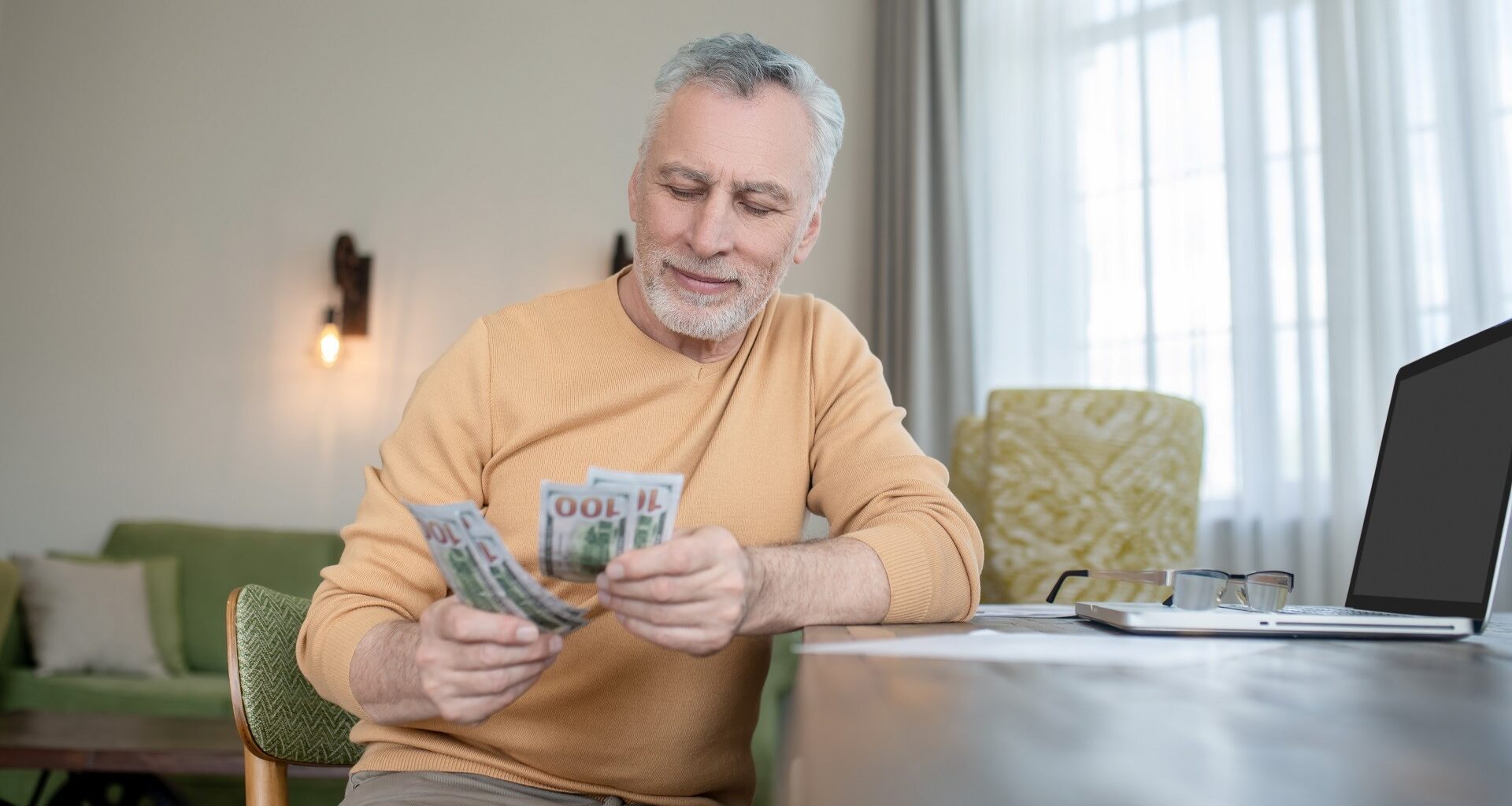 Gray-haired man standing and counting money stock photo