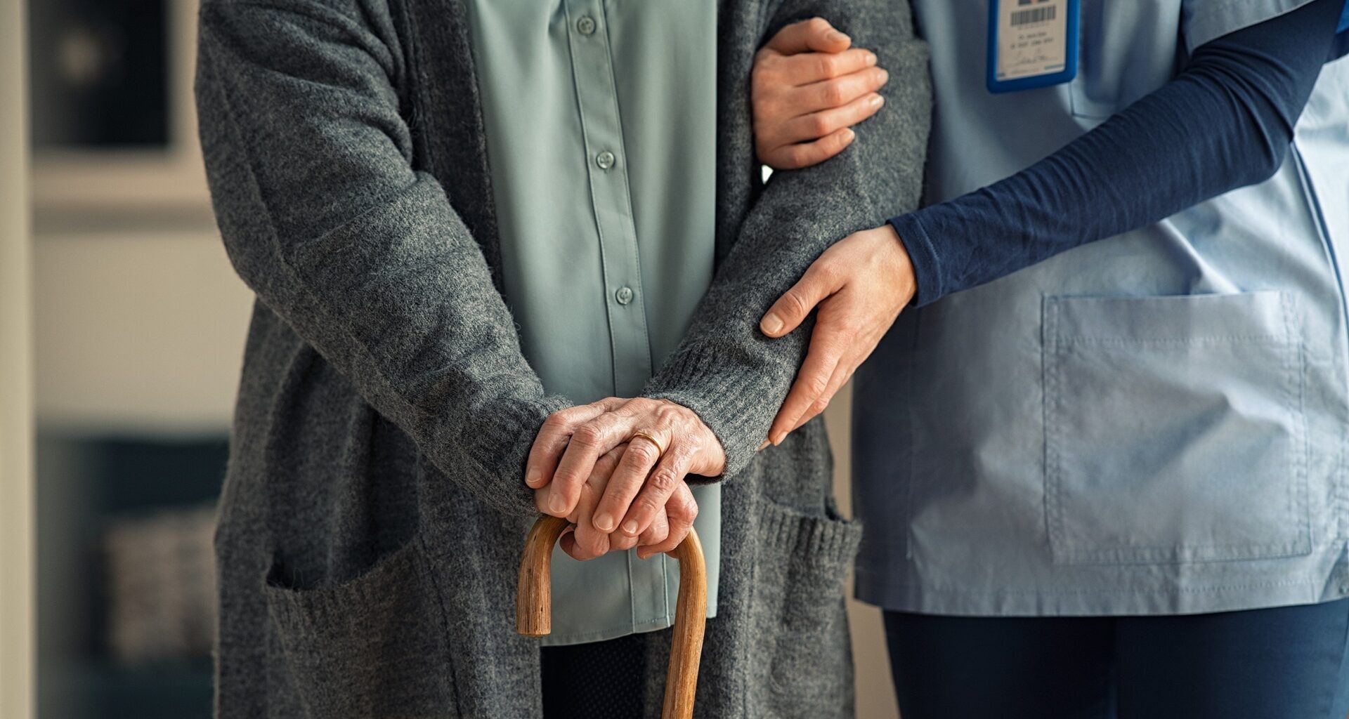 Nurse assisting senior with walking cane stock photo