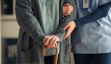 Nurse assisting senior with walking cane stock photo