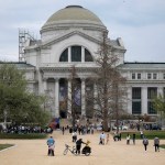 People standing before a tall, classically styled museum building with columns.