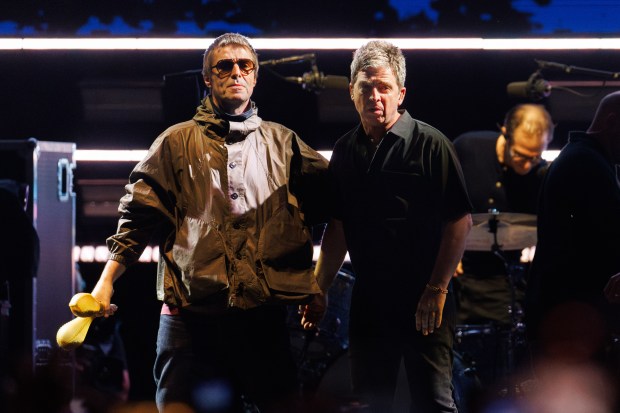 Liam Gallagher, left, and his brother Noel Gallagher walk on...