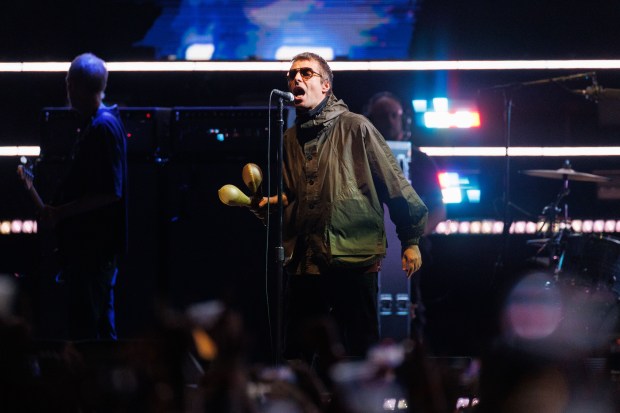 Liam Gallagher, lead singer of Oasis performs with members of...