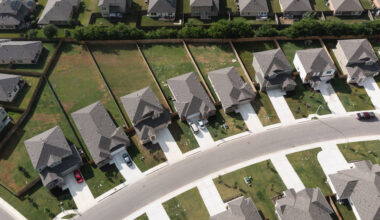 An aerial view of a residential neighborhood in Austin, Texas, USA - grey rooves, white driveways and green lawns.