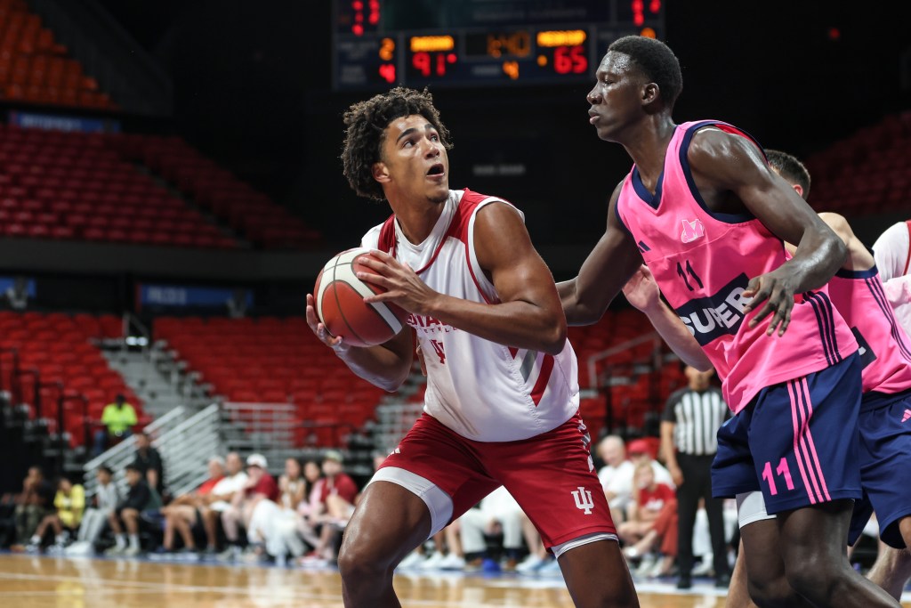 Basketball players in action during a game, one player is preparing to shoot while another is defending.