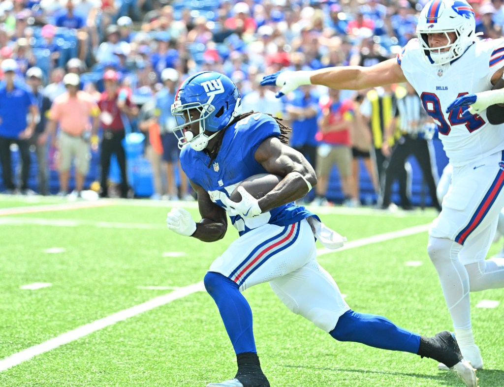 New York Giants running back Dante Miller (25) runs past Buffalo Bills defensive end Landon Jackson (94) in the second quarter at Highmark Stadium.