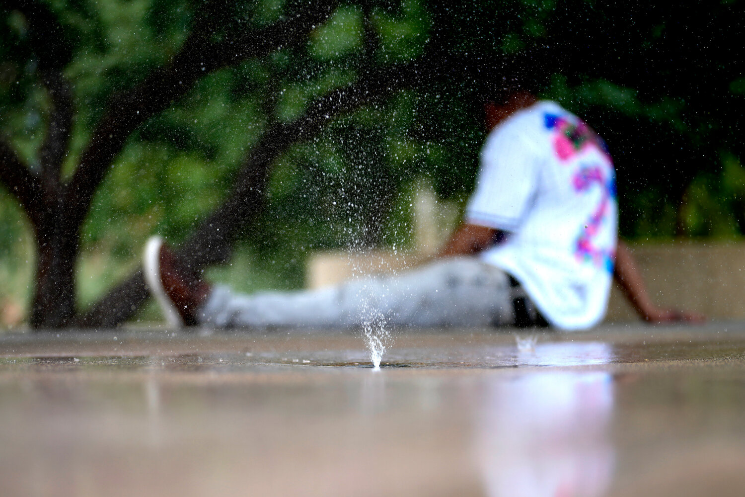 A man who said he was homeless tries to keep cool on a children’s splash pad in Phoenix. Two groups have banded together to help the homeless population near Cesar Chavez Park.