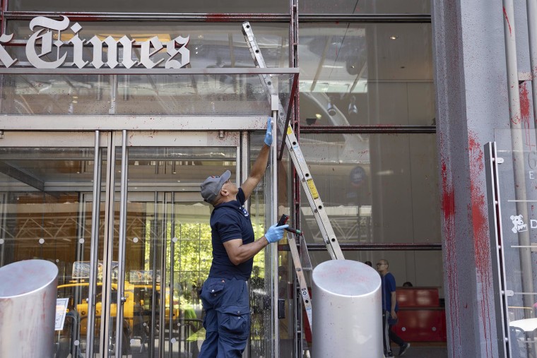 Workers remove red paint splashed across the facade of The New York Times Building on July 30, 2025.