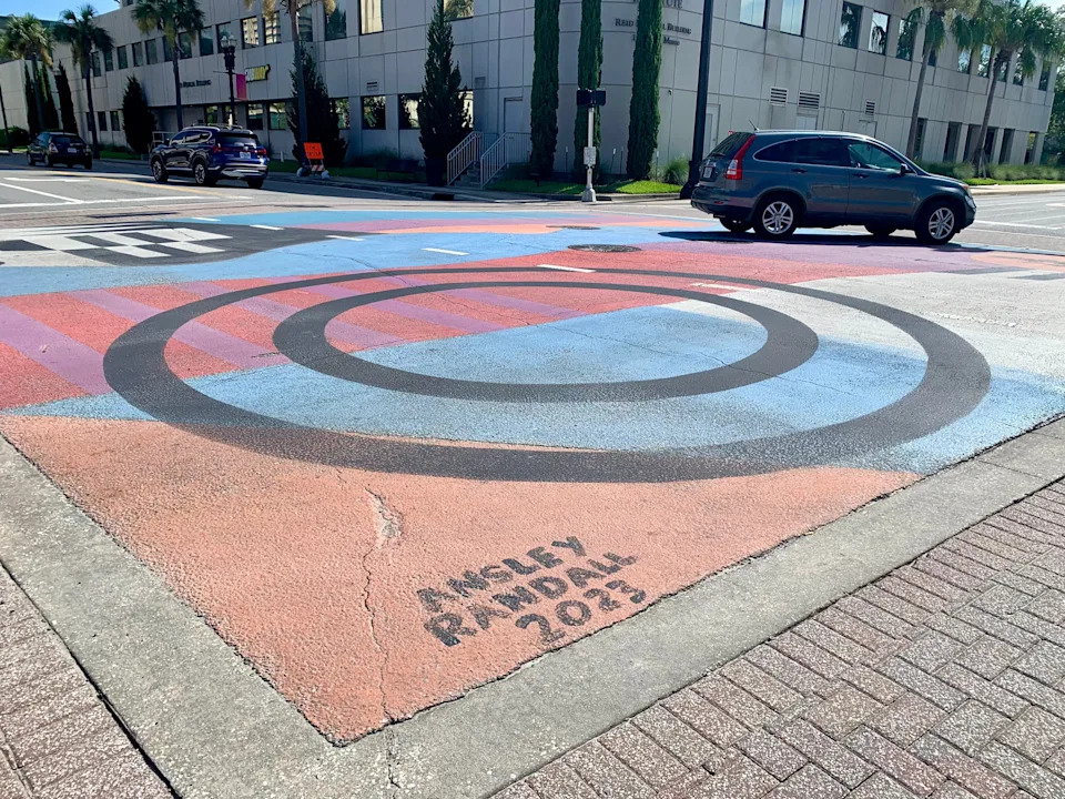 A vehicle turns at the colorful intersection of San Marco Boulevard and Nira Street on July 11 2025 in Jacksonville, Fla. where a mural painted by Neptune Beach artist Ansley Randall has decorated the intersection since 2023.