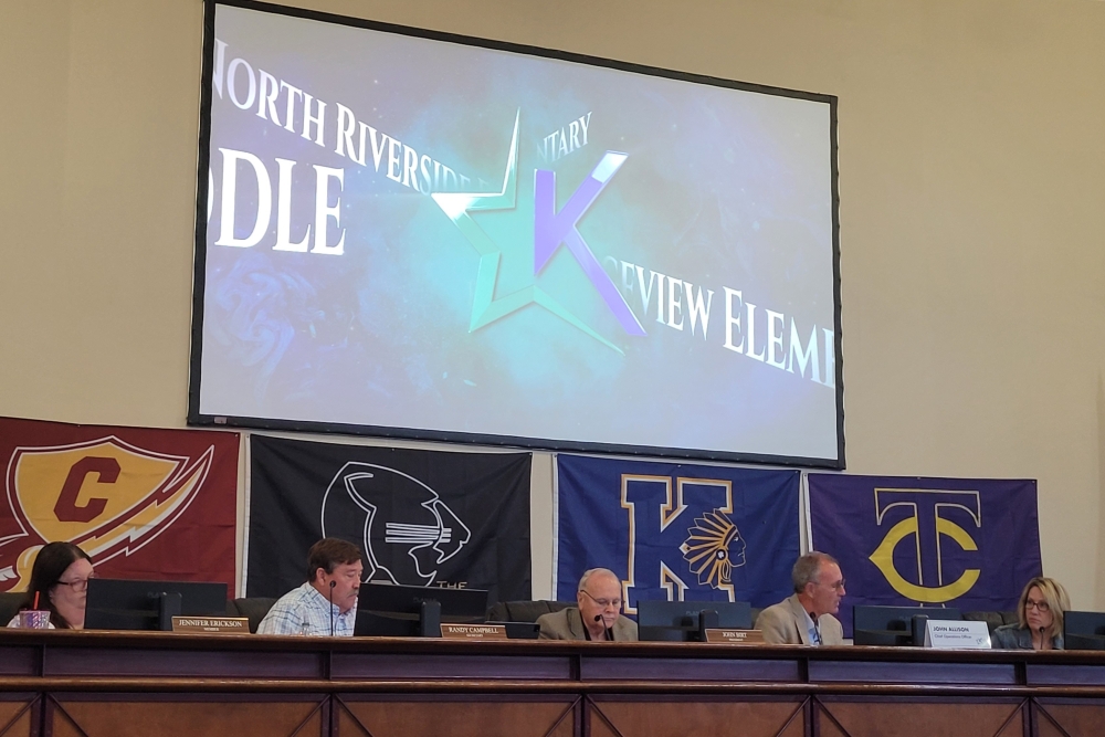 The dais at the Keller Education Center with a screen above the board members.