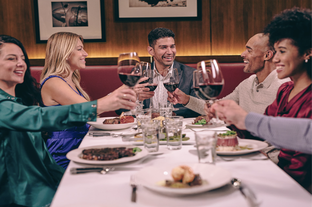 A group clinks wine glasses at a fancy restaurant.