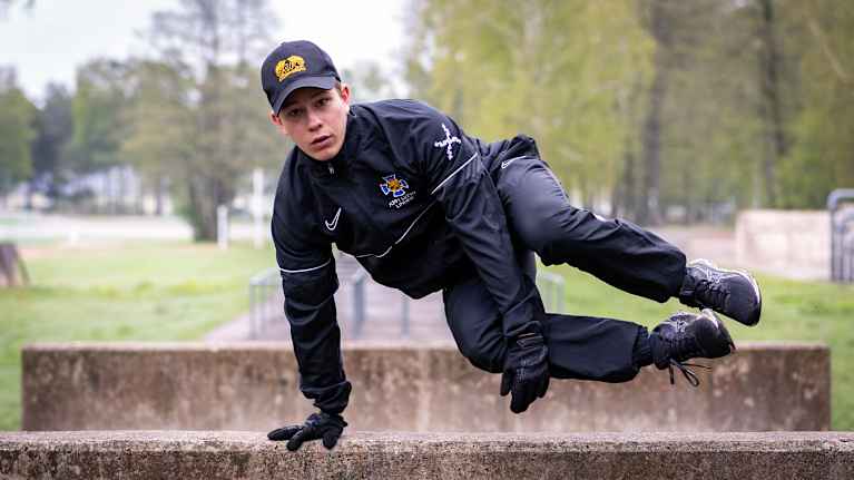 Officer candidate Jesper Linden jumps over a concrete barrier on an army obstacle course.