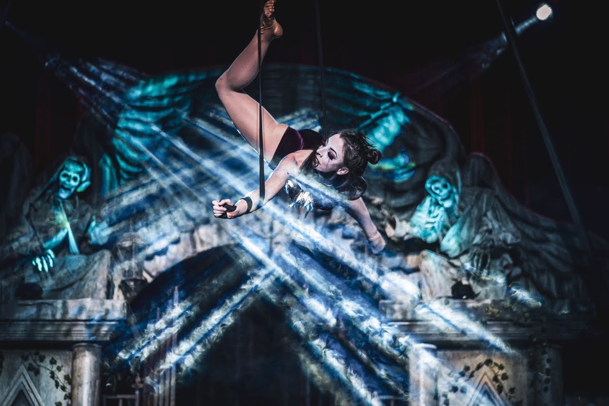 An acrobat swings from a rope