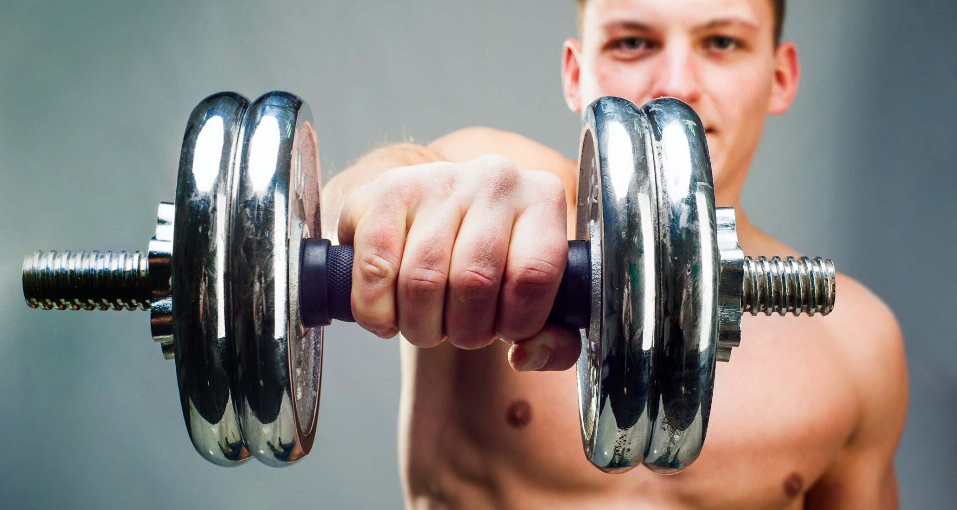 Man holding a dumbbell extended at shoulder height using an overhand grip close-up