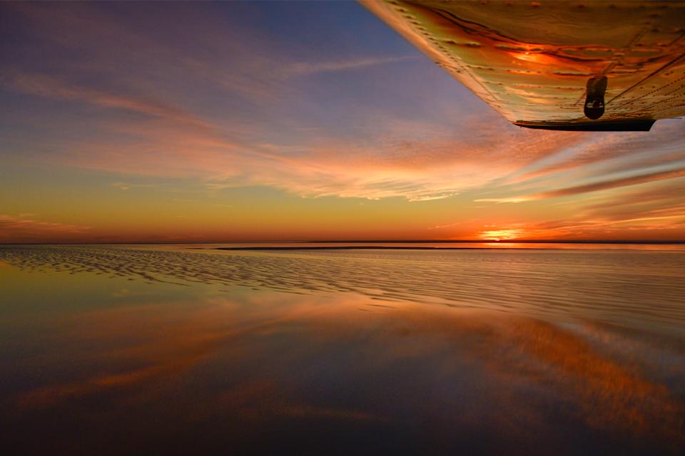 A sunset photo of a plane flying over Kati Thanda-Lake Eyre.