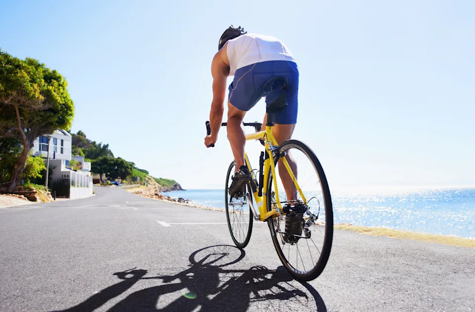 Cropped view of a cyclist cycling along an ocean road
