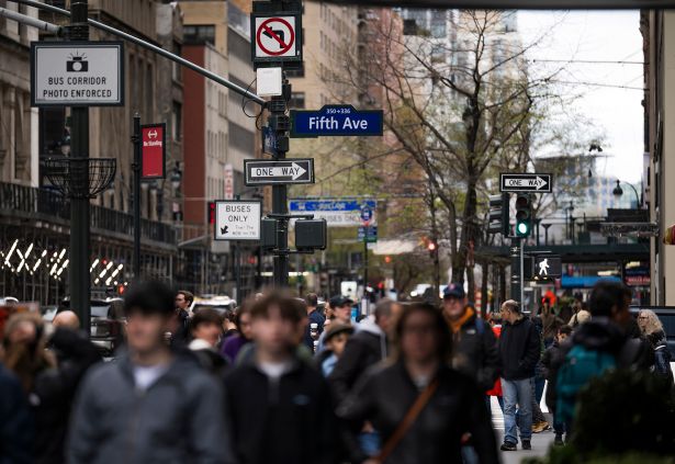 Pedestrians walk past a Fifth Avenue sign in Midtown Manhattan.