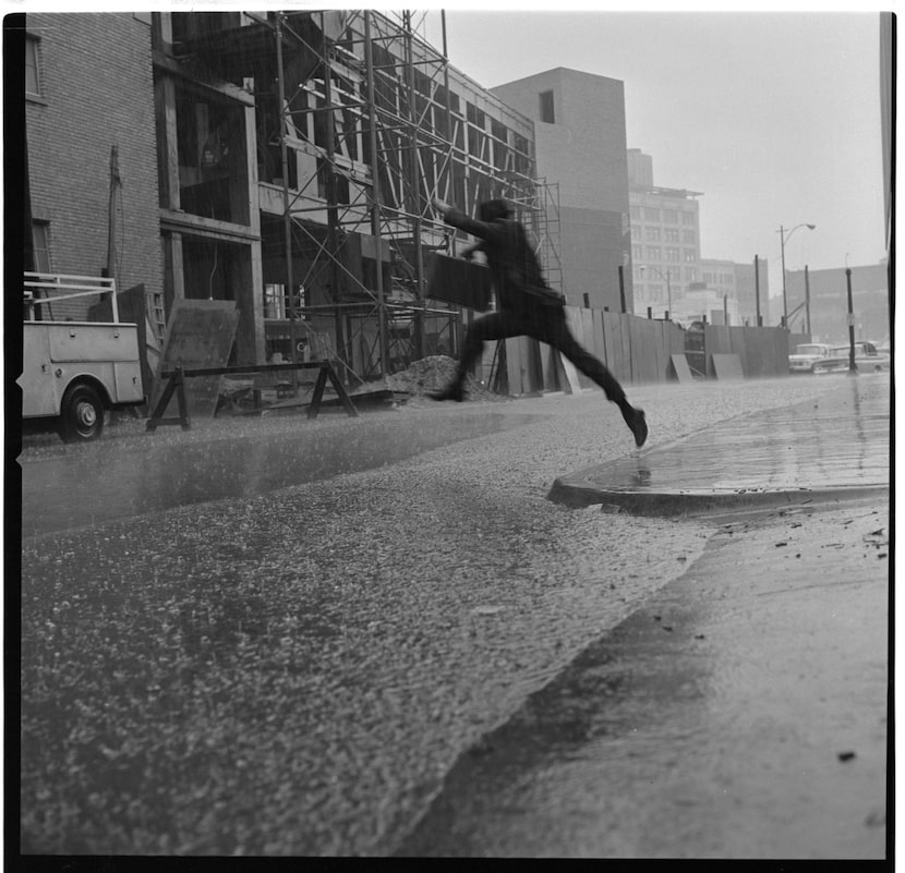 A man leaps across a puddle of water during a Dallas downpour on September 27, 1966.