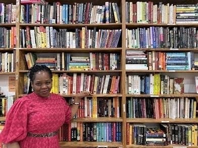Ola Akinmowo standing in front of bookshelf