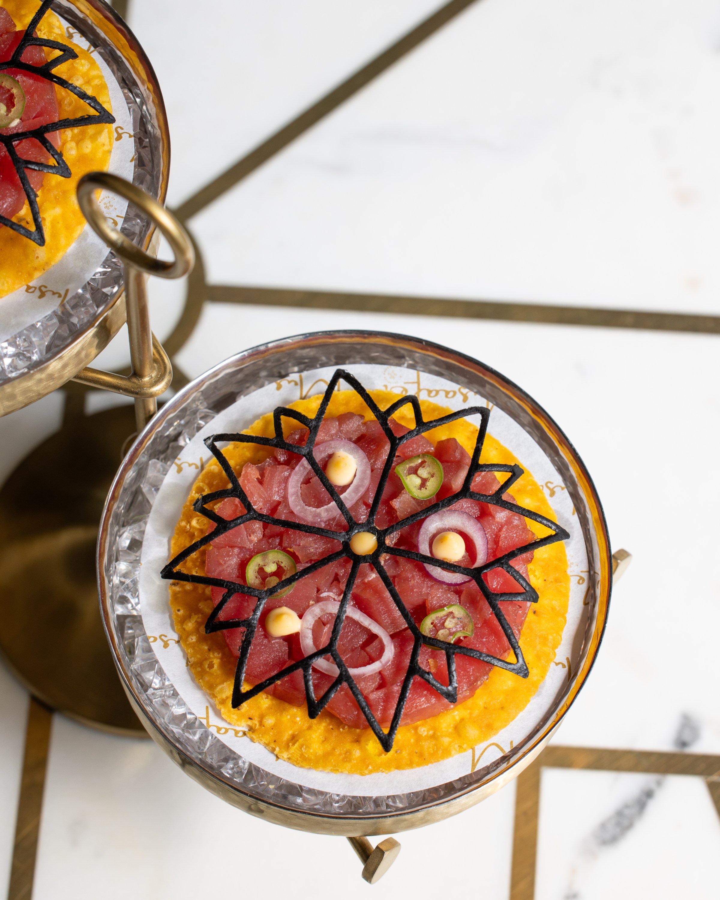 A round tart with tuna and a floral design on top of it.