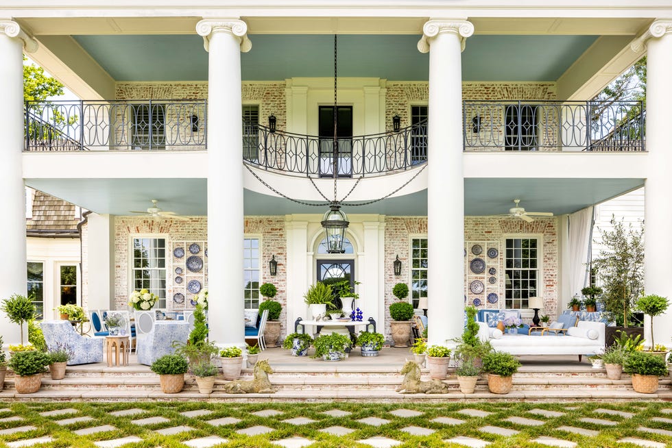 Elegant outdoor patio with white columns and seating among potted plants.
