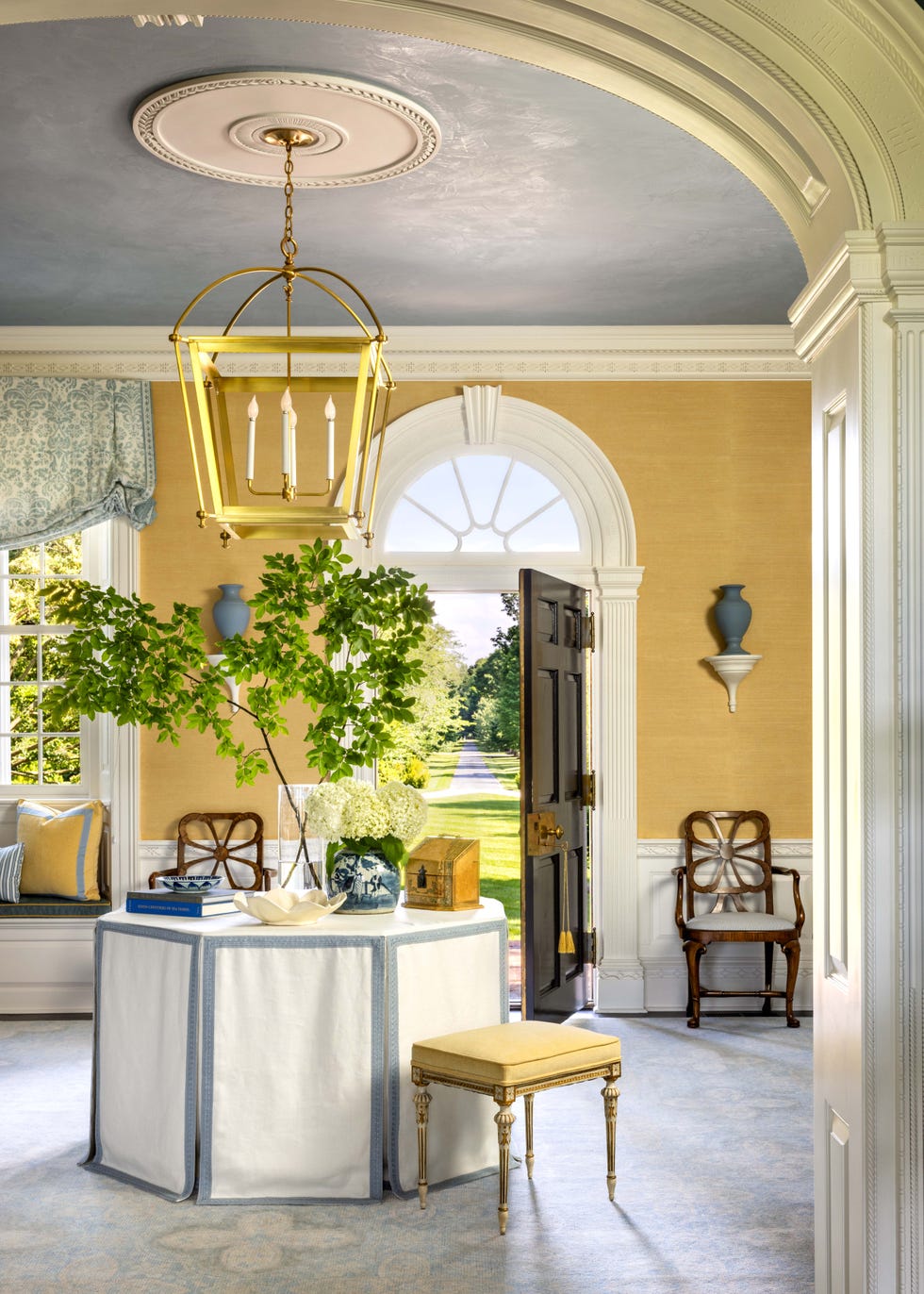 Interior view of a welcoming room featuring a circular table and a doorway leading to a garden pathway.
