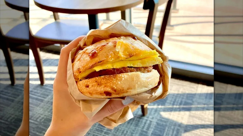 Hand holding asiago sausage and egg sandwich