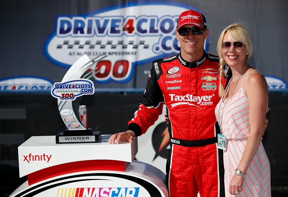 Kevin Harvick, driver of the #88 taxslayer.com Chevrolet, and his wife DeLana celebrate in Victory Lane after winning the NASCAR XFINITY Series Drive4Clots.com 300 at Auto Club Speedway on March 21, 2015.
