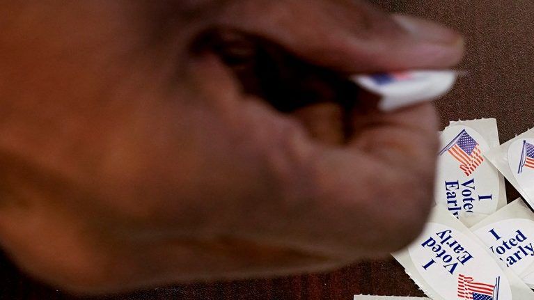 A voter takes a sticker after casting an early ballot at a polling station. (AP Photo/Morry Gash)
