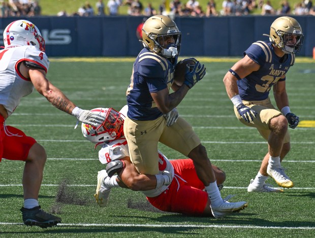 Navy's TK Hodges picks up a first down on a run before being brought down by VMI's Steven Riveros in the fourth quarter. The Navy Midshipmen win their NCAA football season opener at home against the visiting VMI Keydets, 52-7, at Navy-Marine Corps Memorial Stadium in Annapolis. (Paul W. Gillespie/Staff)