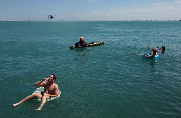 An AH-64 Apache helicopter hovers above Lake Michigan as people watch the Chicago Air and Water Show from the water in the 2300 block of the Lakefront Trail on Aug. 10, 2024, in Chicago. (John J. Kim/Chicago Tribune)