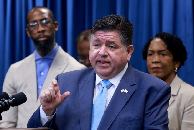 Flanked by several elected officials, Gov. JB Pritzker speaks and answers questions from the media on July 28, 2025, after signing two bills advancing his agenda of common sense gun laws and improving safety in Illinois communities. (Antonio Perez/Chicago Tribune)