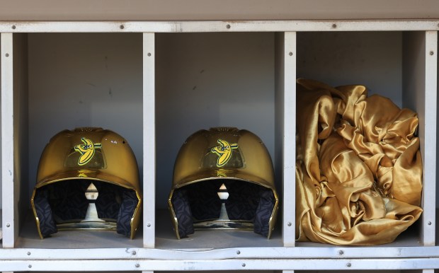 Savannah Bananas player helmets and a cape are stored in the dugout shelf before a game against the Firefighters on Aug. 15, 2025, at Rate Field. (John J. Kim/Chicago Tribune)