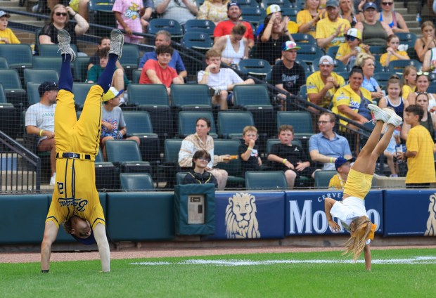 Savannah Bananas player Jared Donalson performs a handstand next to a young fan before a game against the Firefighters on Aug. 15, 2025, at Rate Field. (John J. Kim/Chicago Tribune)