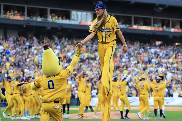 Savannah Bananas player Dakota Albritton (14) high-fives team mascot Split before a game against the Firefighters on Aug. 15, 2025, at Rate Field. (John J. Kim/Chicago Tribune)
