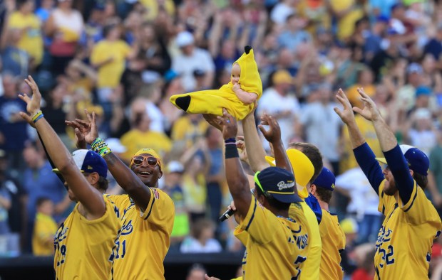 A "banana baby" is introduced as Savannah Bananas players surround her during a ceremony before a game against the Firefighters on Aug. 15, 2025, at Rate Field. (John J. Kim/Chicago Tribune)